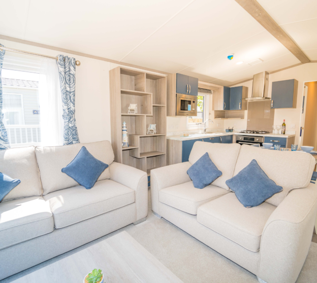 Inviting interior of a static home with two blue sofas, a coastal-themed dining area, and a picturesque window offering scenic views.
